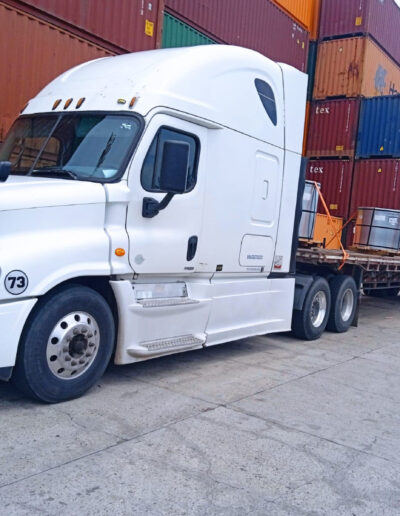 Tractocamión blanco frente a contenedores